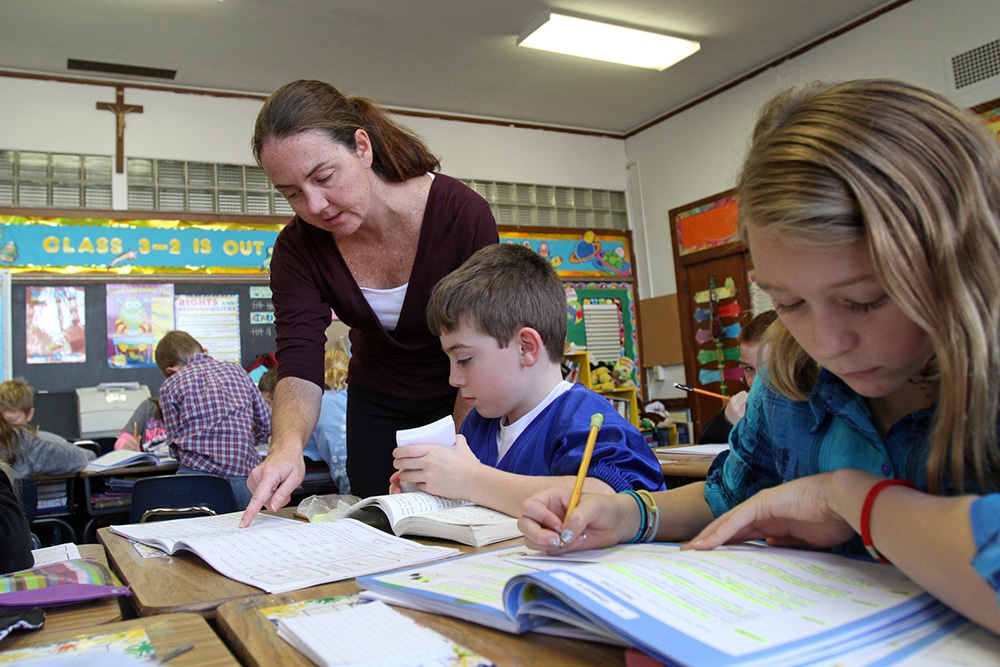 TEACHER WORKS WITH STUDENTS AT CATHOLIC SCHOOL IN NEW YORK