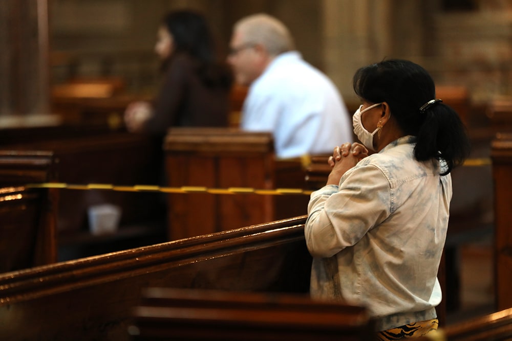 WOMAN PRAYS MASS COVID-19 LONDON CHURCH