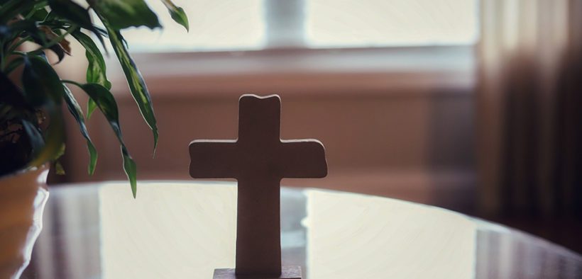 A cross on a glass table-concept bless our home