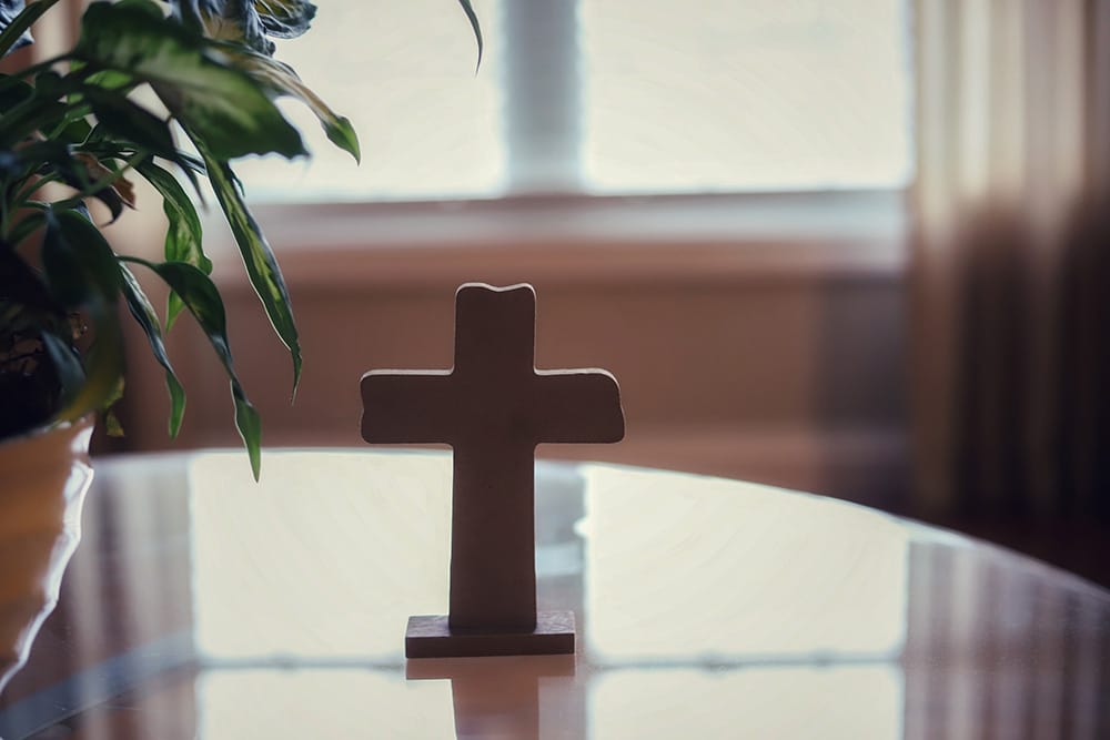 A cross on a glass table-concept bless our home