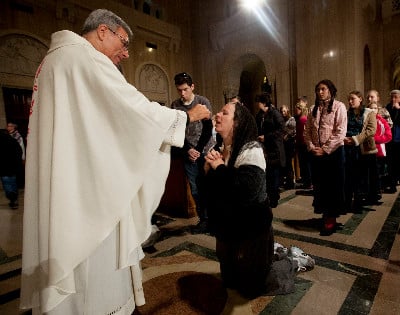 Woman kneels to receive Communion