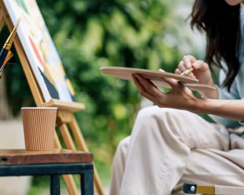 An artist sits are her easel.