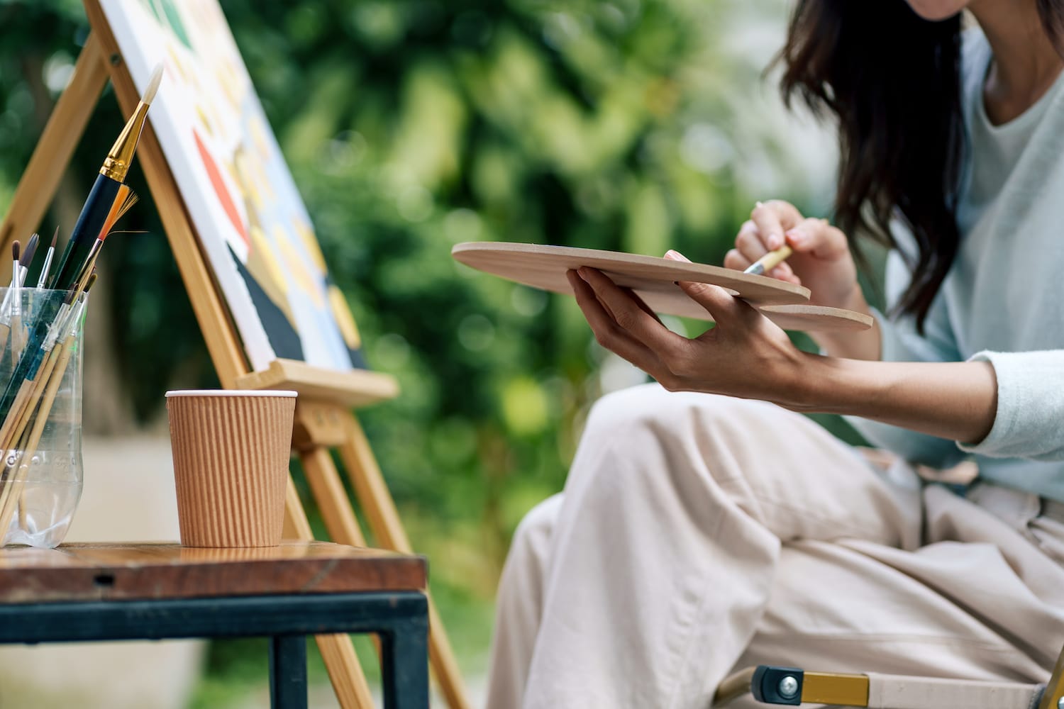 An artist sits are her easel.