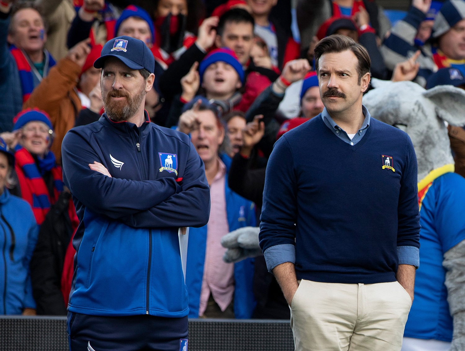 This is a scene from the TV show "Ted Lasso" with stars Brendan Hunt as Coach Beard on the left and Jason Sudeikis as Coach Ted Lasso on the right.