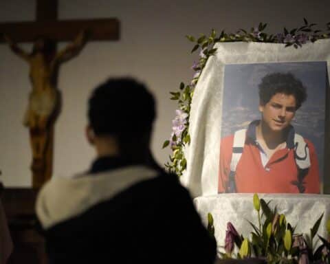 A person looks at a portrait of young Carlos Acutis