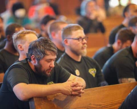 Two men in dark t-shirts attend a Workers Mass