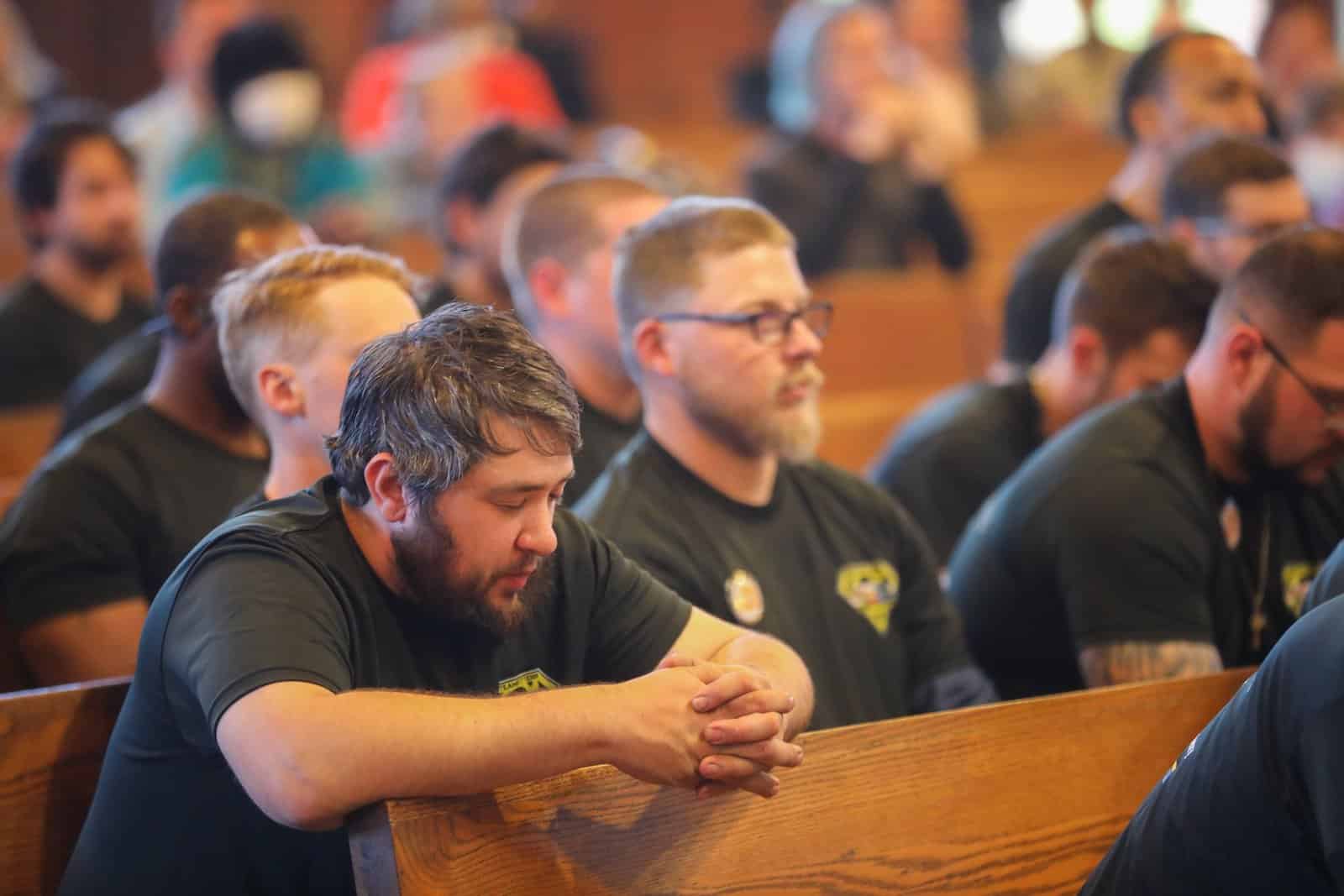 Two men in dark t-shirts attend a Workers Mass
