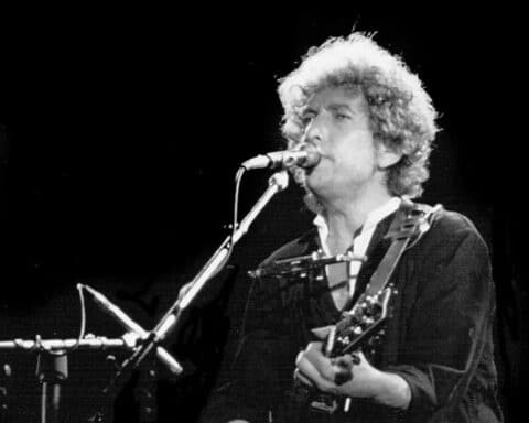A black and white image of singer Bob Dylan performing.